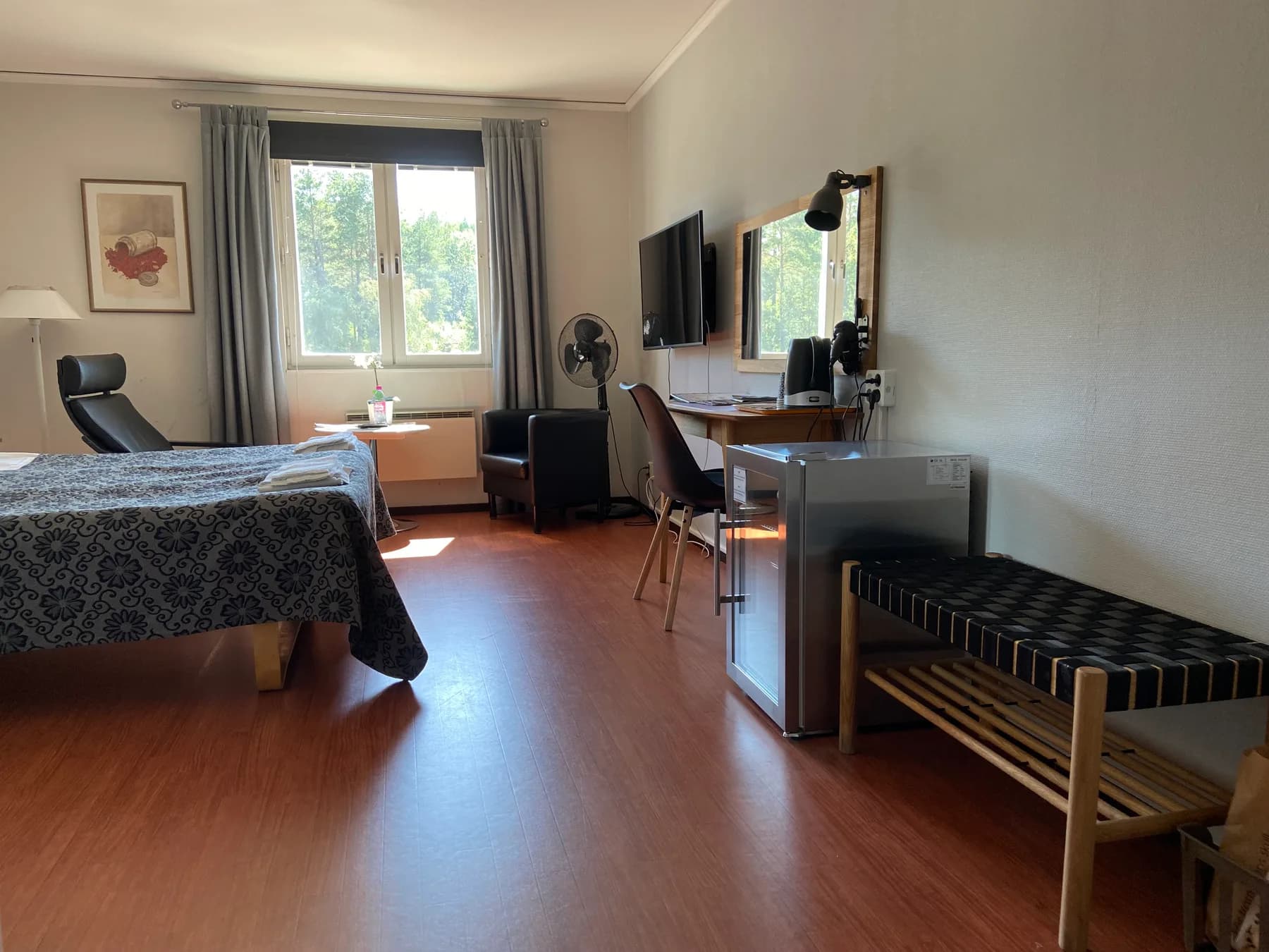 Hotellrum med säng, skrivbord, tv och bagagebänk