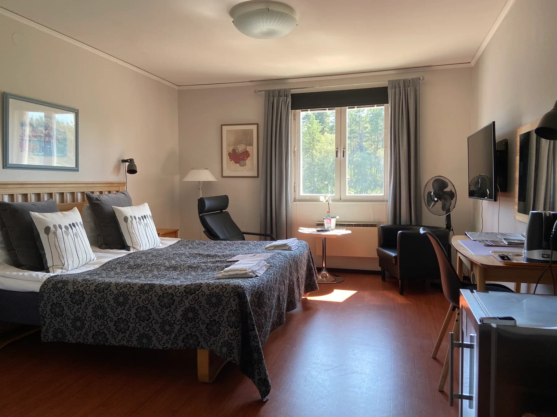 Hotellrum med två bäddade sängar, skrivbord och fåtöljer